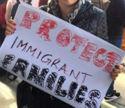 Woman holds a handmade protest sign reading "Protect Immigrant Families"